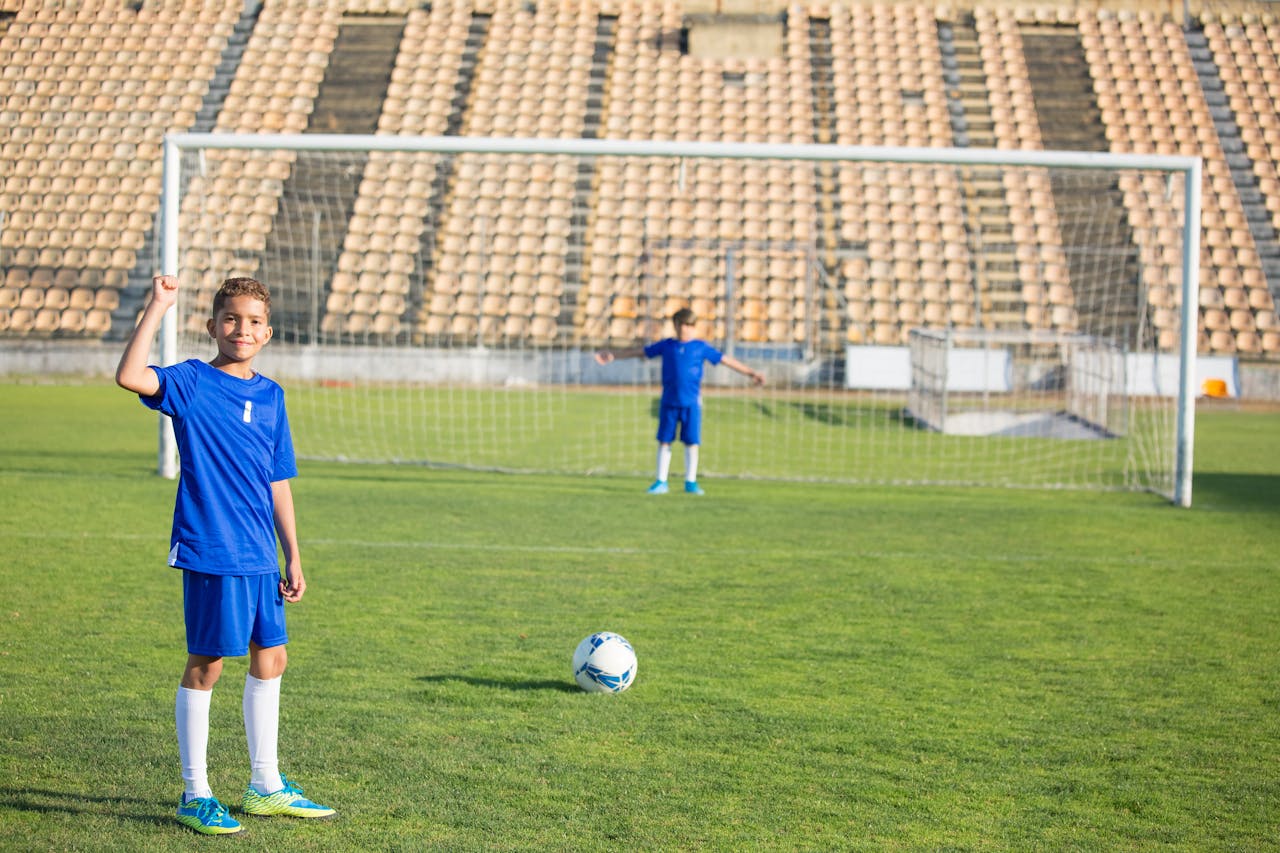 Two young boys playing soccer on a grassy field under clear skies. Perfect for sports themes.